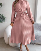 Pink pleated dress worn by a person in a minimal indoor setting