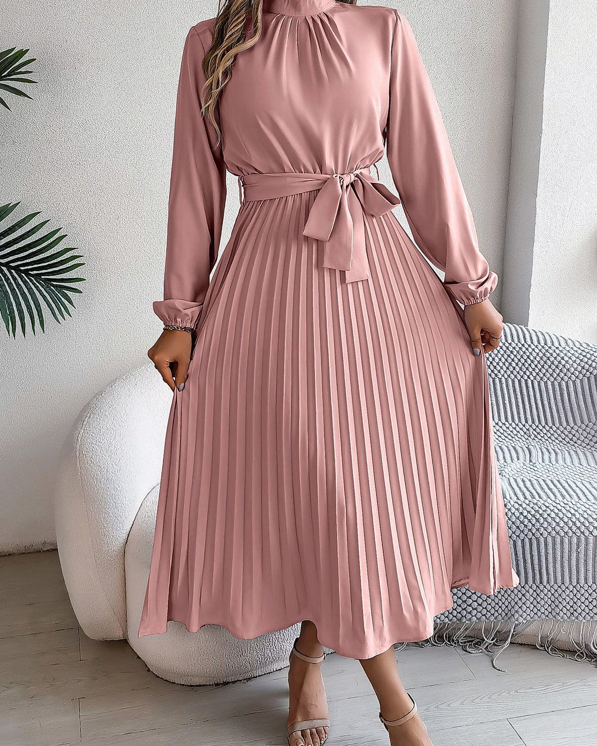 Pink pleated dress worn by a person in a minimal indoor setting