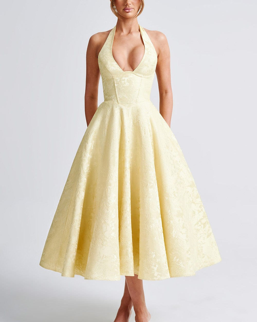 Woman wearing a yellow halter neck dress on a white background