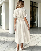 Woman wearing a beige dress walking on a tiled patio.