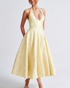 Woman wearing a yellow halter neck dress on a white background