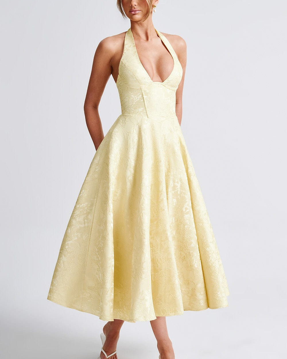 Woman wearing a yellow halter neck dress on a white background