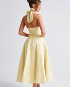 Woman wearing a yellow dress with a bow detail on a white background