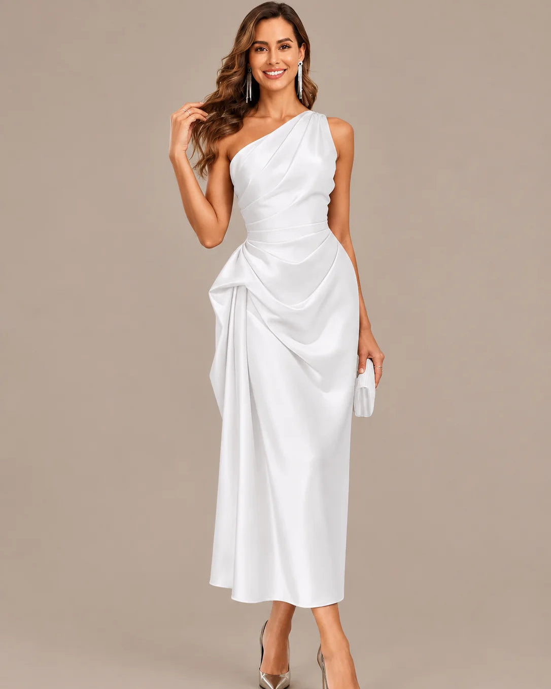 A woman modeling a white one-shoulder midi dress with draped fabric details, paired with metallic high heels and a matching clutch, against a solid beige studio background.