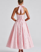 Pink dress with a bow detail on the back, worn by a person against a plain background