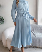 Woman wearing a light blue dress with long sleeves in a room.
