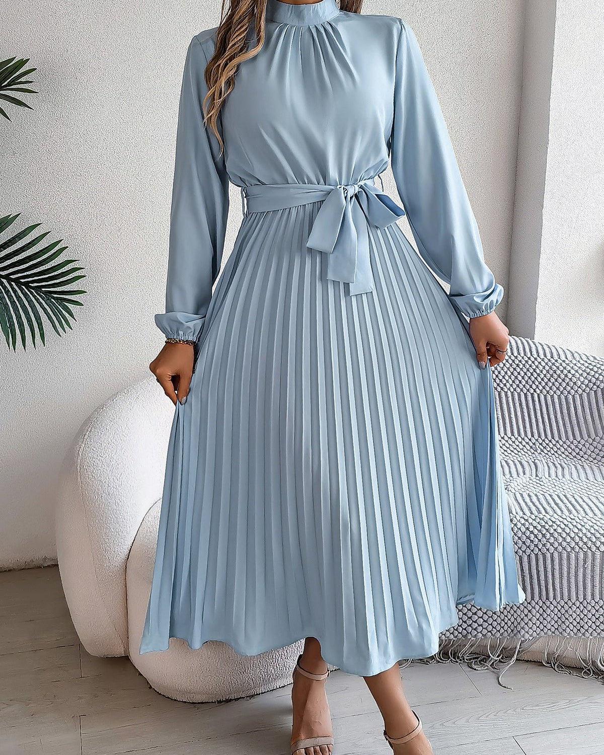 Woman wearing a light blue dress with long sleeves in a room setting.