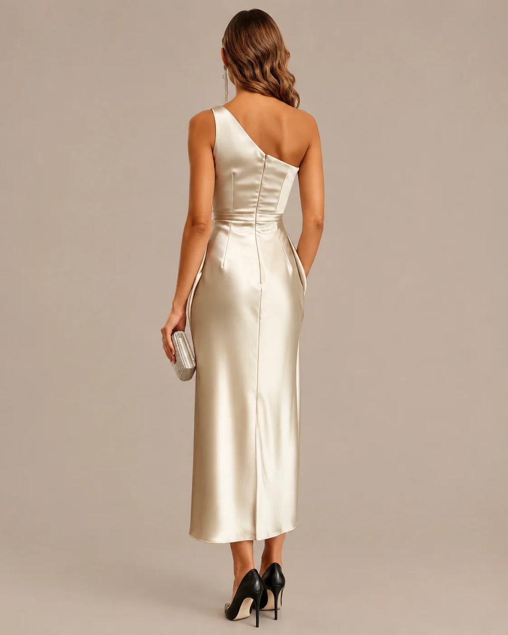 A woman shown from the back wearing a one-shoulder satin midi dress in a warm champagne or cream tone. The dress has a structured corset-style waist and a single strap across the upper back.