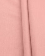 A close-up of dusty pink fabric with a visible woven texture and soft folds.