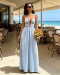 Woman in a blue and white striped dress holding flowers in a restaurant with a beach view.