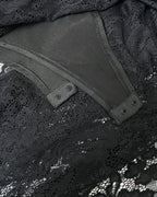 Close-up of a black lace garment with a smooth dark gray or charcoal inner panel and snap-button tabs.