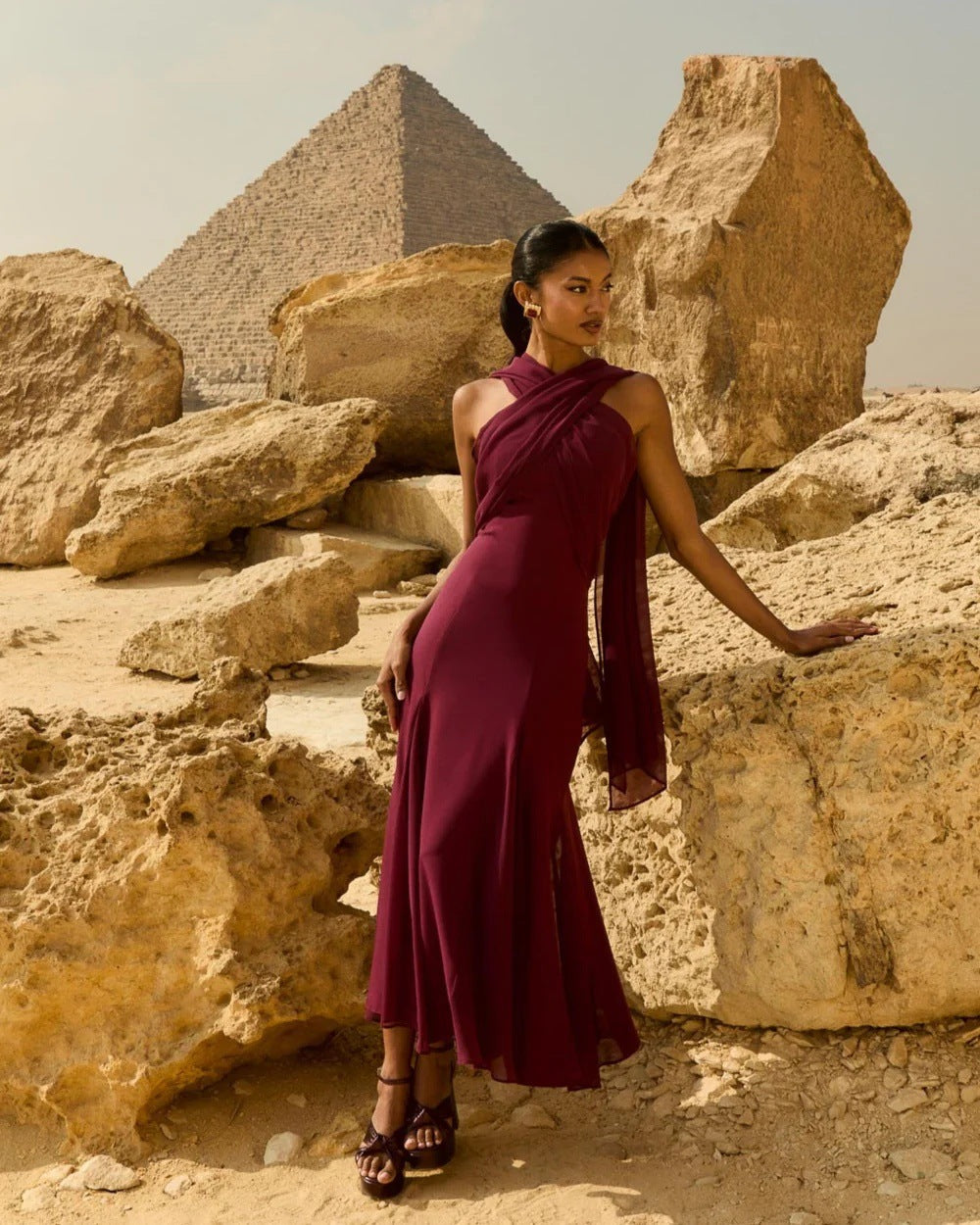 Woman in a burgundy dress standing in front of the pyramids