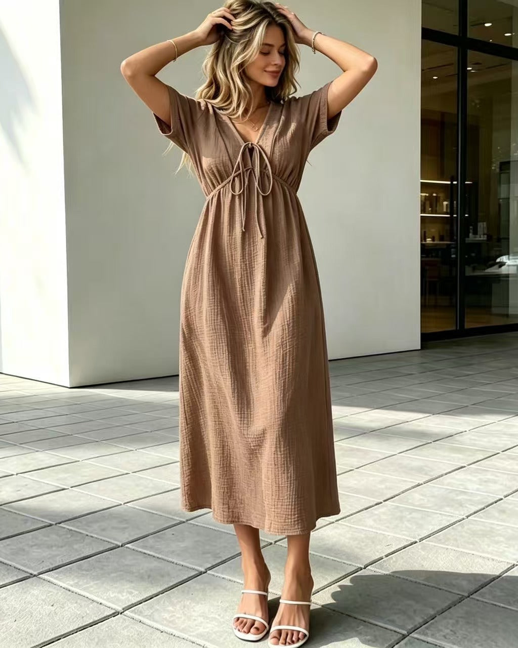 Woman wearing a brown dress standing on a tiled patio.
