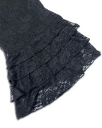 Close-up of a black lace garment with layered ruffles on a plain white background.