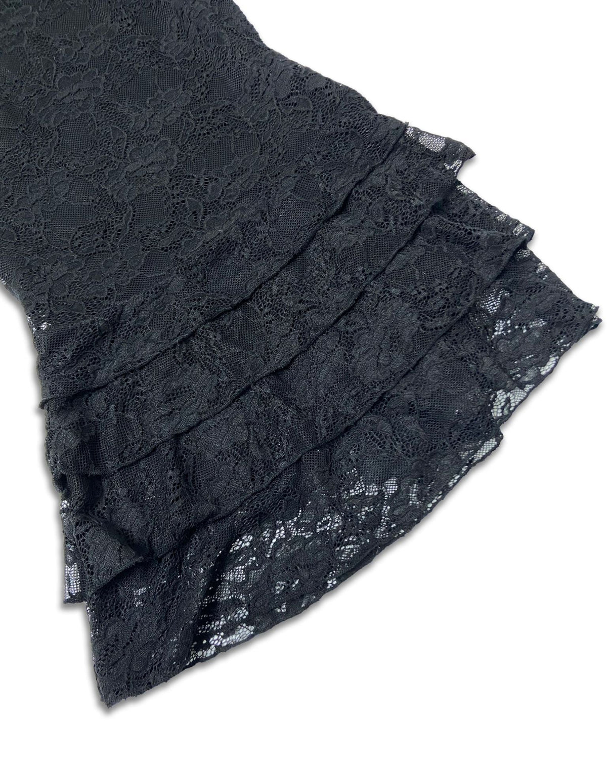 Close-up of a black lace garment with layered ruffles on a plain white background.