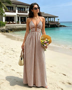 Woman in a striped dress standing on a beach with a resort in the background