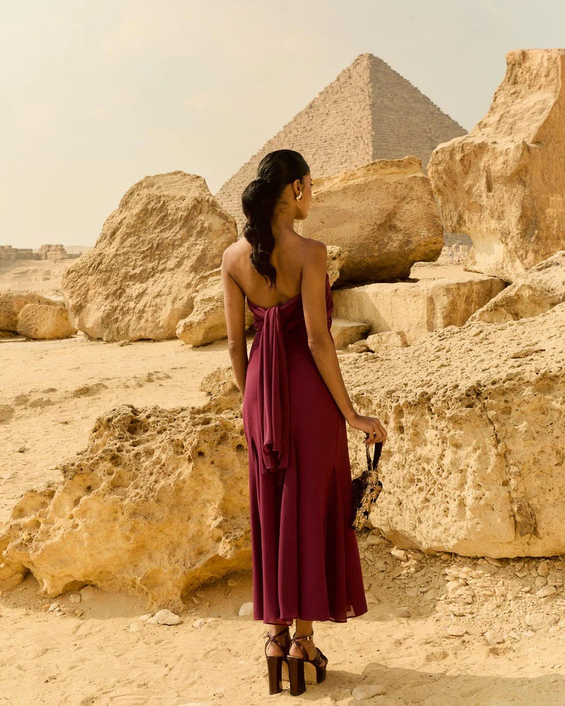 Woman in a burgundy dress standing in front of the Pyramids of Giza.