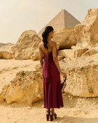 Woman in a burgundy dress standing in front of the Pyramids of Giza.