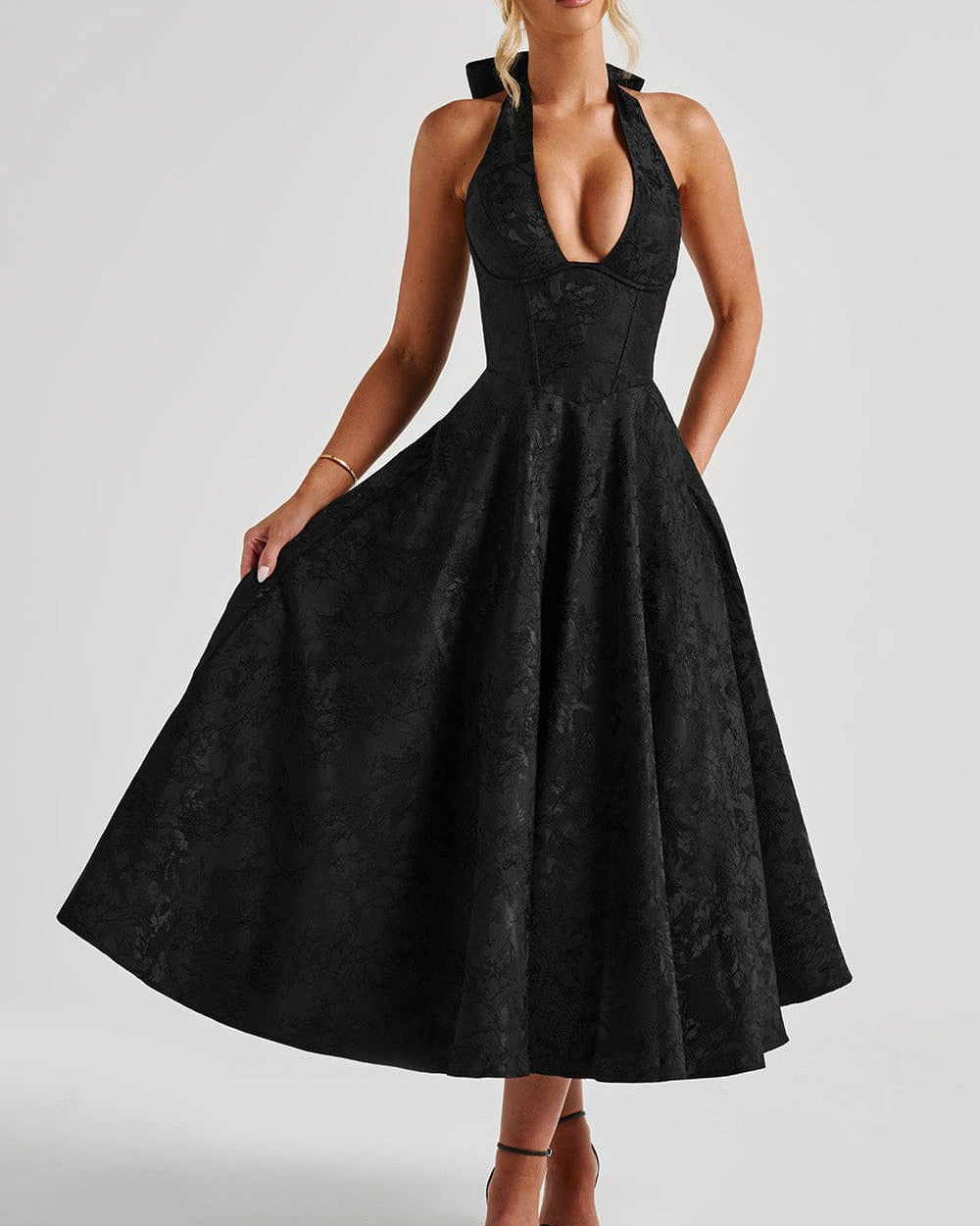Black dress with a halter neckline on a plain background