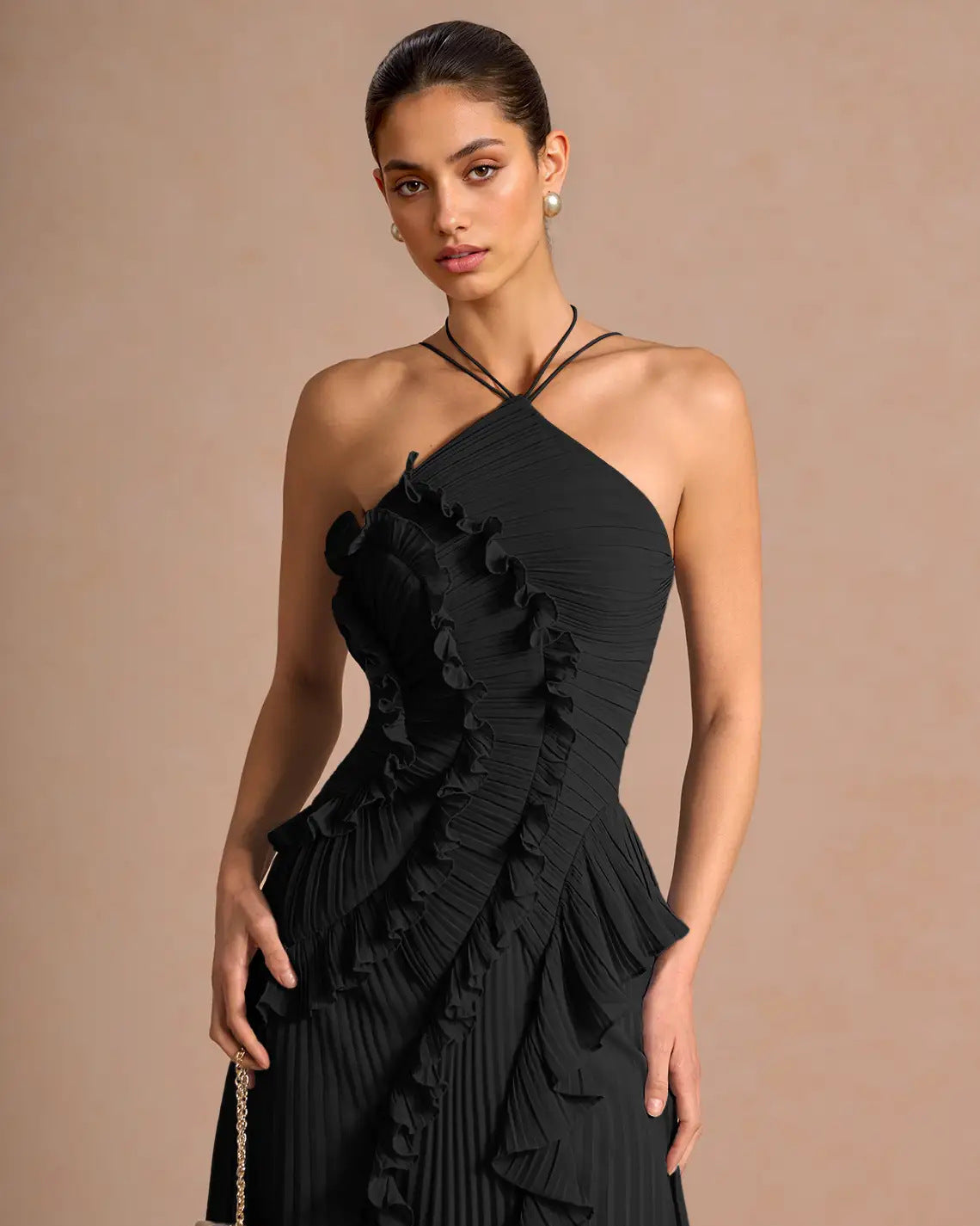 Woman wearing a black ruffled dress against a beige background